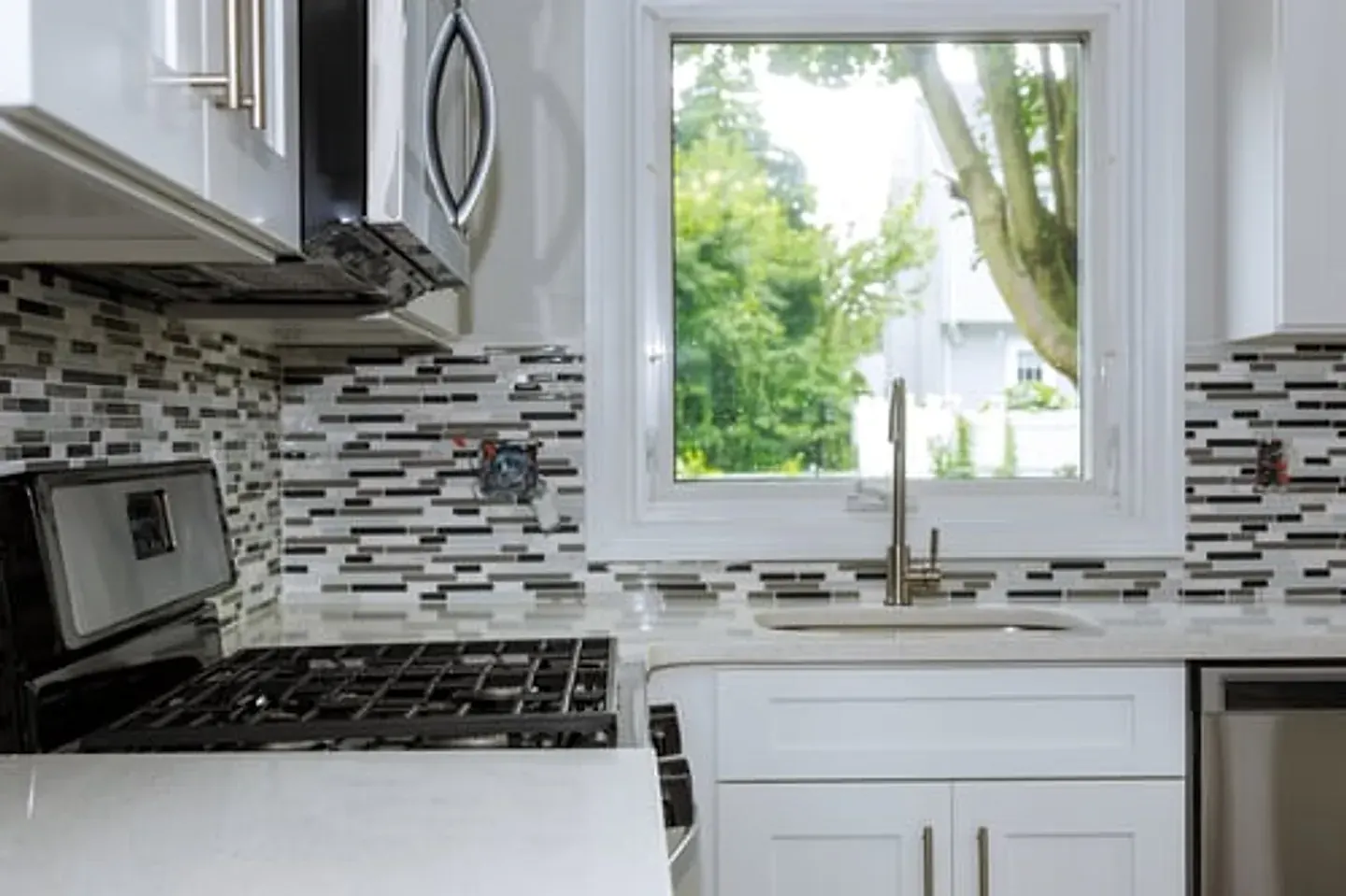 Remodeled kitchen with tile backsplash and quartz countertops