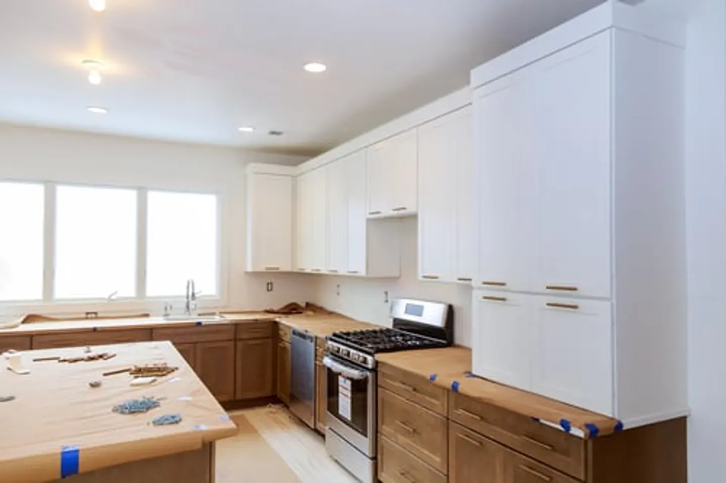 Kitchen remodel in progress with new white and wood cabinetry